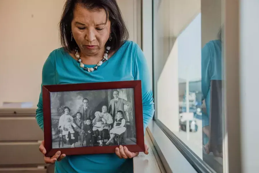 梅琳达·Yee富兰克林 holding a photograph of her family.