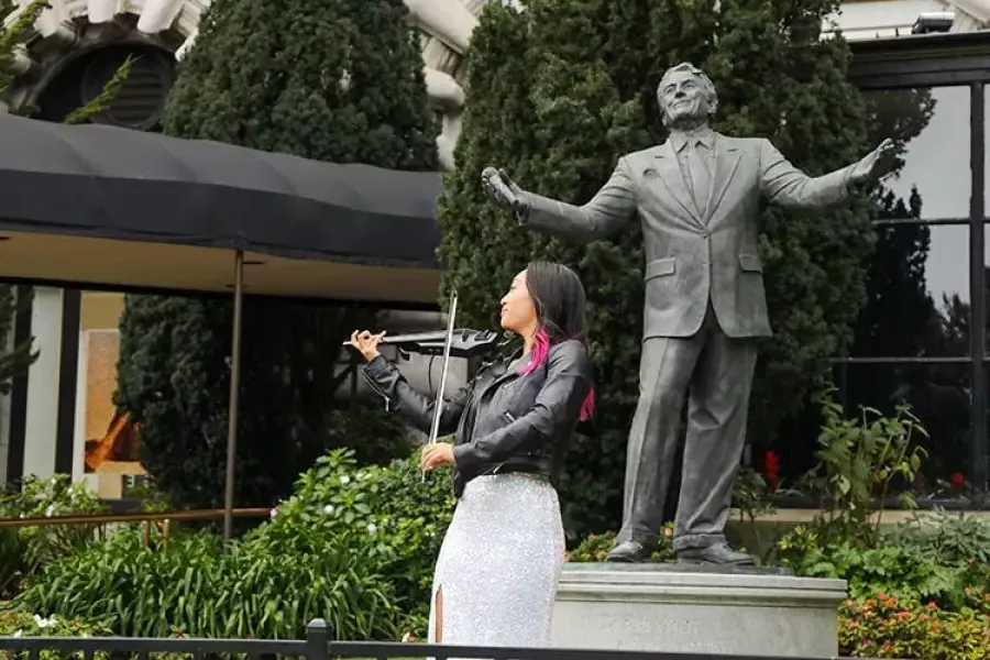 A woman plays the violin in front of the Tony Bennett statue at the 费尔蒙特酒店.