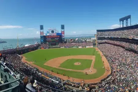 A view of San Francisco's Oracle Park looking out from the st和s, with the baseball diamond in the foreground 和 San Francisco Bay in the background.