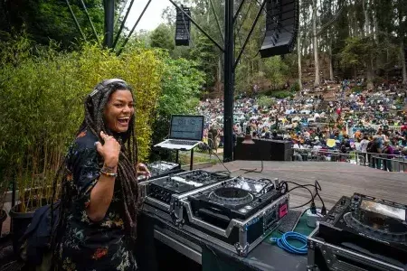 A woman DJing at the 斯特恩林 Festival looks over her shoulder and smiles into the camera.