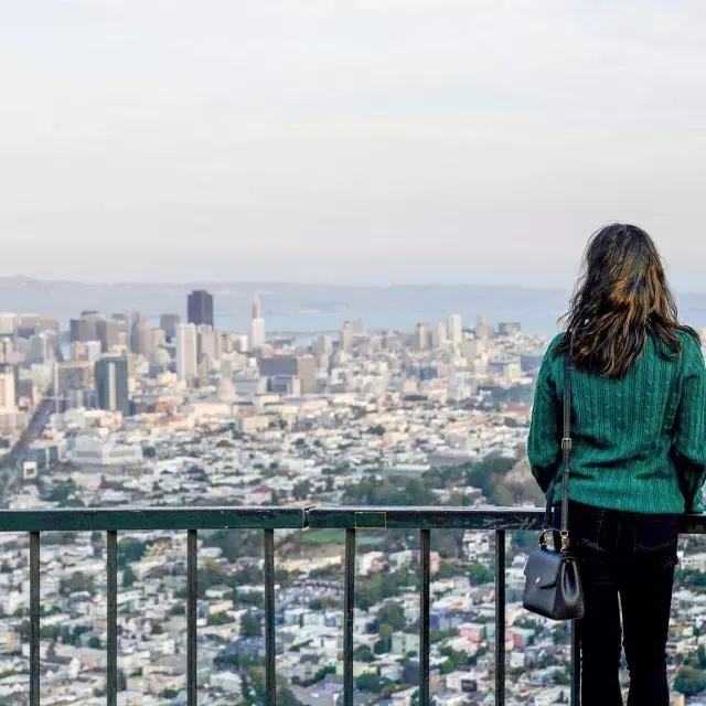 Eine Frau blickt von Twin Peaks aus auf die Skyline von San Francisco.