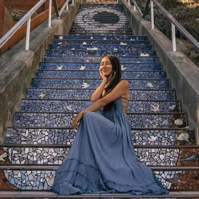 サンフランシスコのサンセット地区にある16番街のタイル張りの階段に座ってポーズをとる女性。